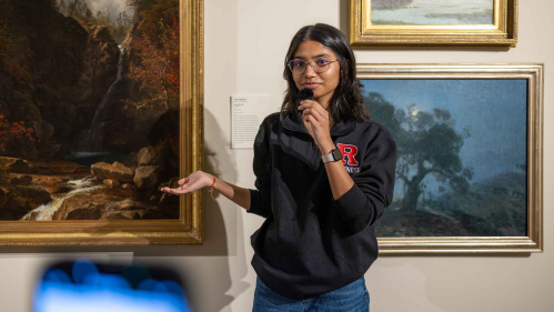 A smartphone records Rutgers sophomore Aditi Sandhir discuss a painting on the wall at the Zimmerli Art Museum.