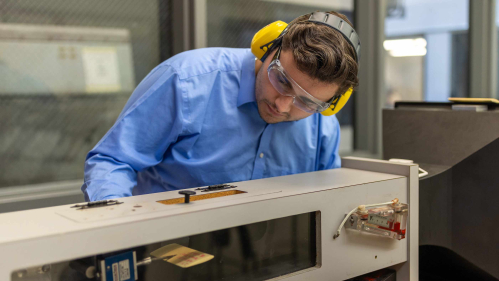 Wearing earmuffs and safety glasses, Rutgers-New Brunswick senior Doug Doyle operates and miniature wind tunnel in a School of Engineering lab on Busch campus.
