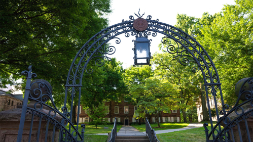 Old Queens, seen through the Class of 1902 Gate, is obscured by lush trees during the summer months.