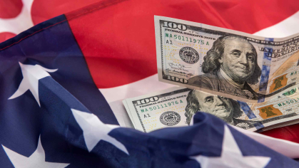 A portion of a flag is seen with Ben Franklin's - $100 bills scattered.