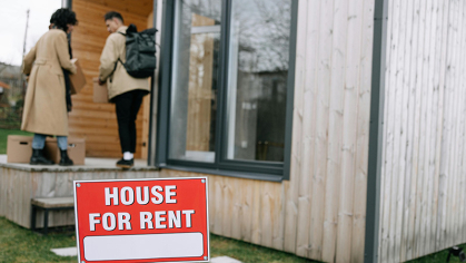House for rent sign with tenants in the background