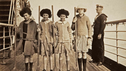 Four girls playing shuffleboard pose for a photograph in this undated black-and-white image.