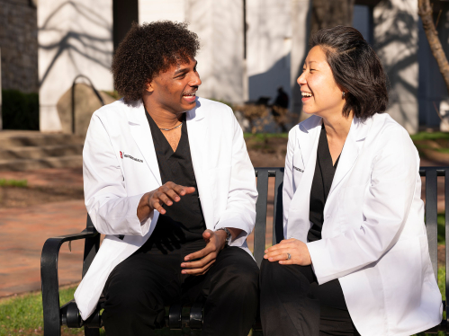 Rutgers school of nursing students chat on a bench outside