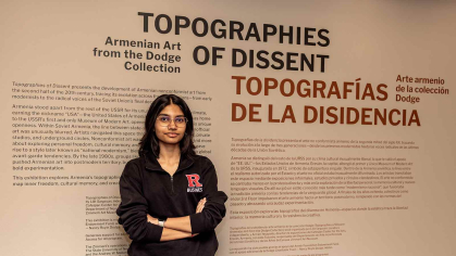 Rutgers sophomore Aditi Sandhir leans against a wall of signage at the Zimmerli Art Museum.
