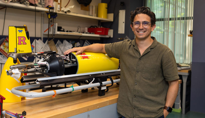 Man stands in oceanography lab in front of a glider.