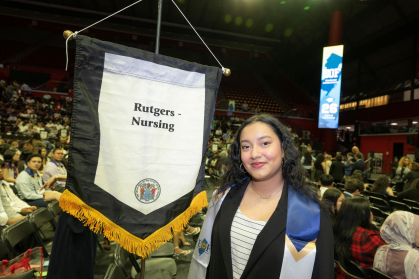 Sofie Mangru stands in front of a sign that reads "Rutgers-Nursing" during the ceremony for Education Opportunity Fund