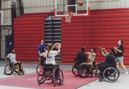 Participants of True Grit summer camp, who are in wheelchairs, along with counselors play basketballba