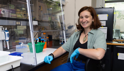 A woman in a lab wears blue lab gloves