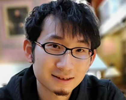 Close-up of scientist wearing glasses and a black shirt.