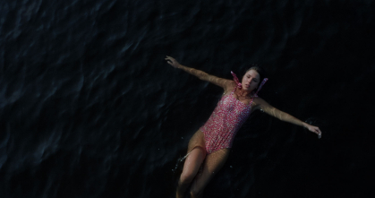 A young woman floats on her back in a body of water in a scene from "Your Lips Never Left Mine."