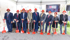 Dignataries in hard hats holding shovels at the groundbreaking 